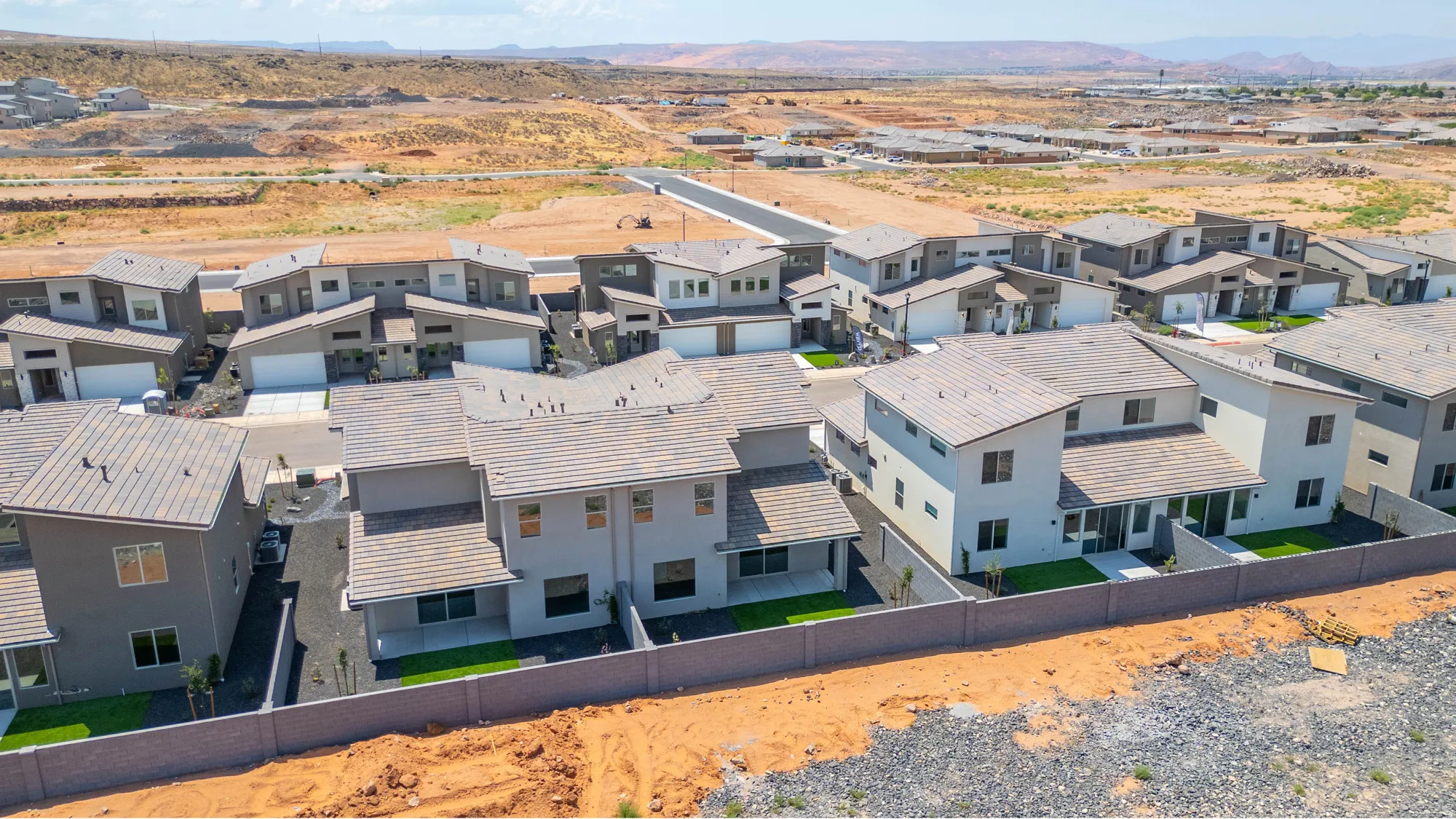 Modern residential development with uniform architectural styles, privacy fencing, and structured landscaping