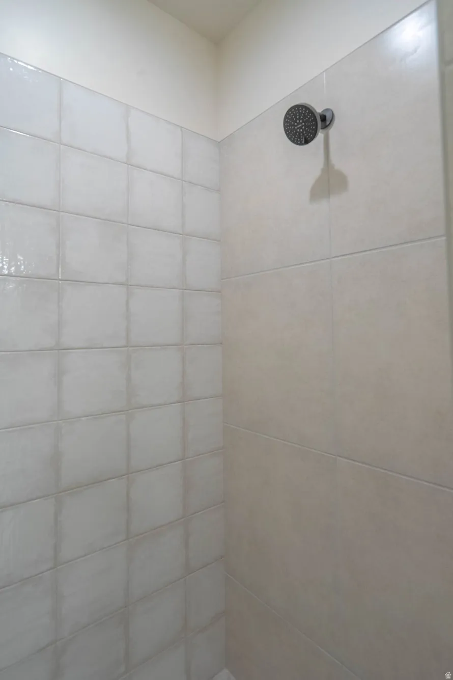 Shower stall featuring large format and square wall tiles with a dark finish shower head