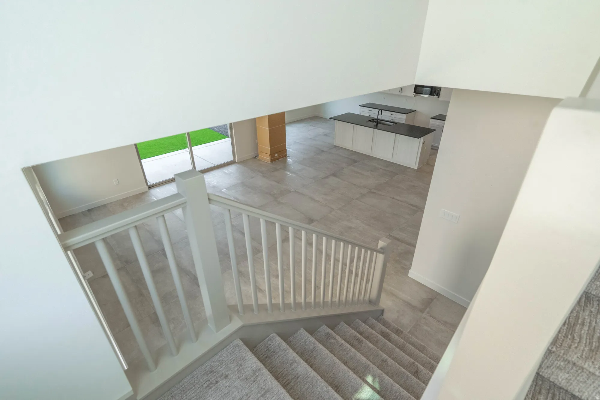 Open-concept layout with tile flooring, white shaker cabinetry, dark countertops, and a sliding glass door