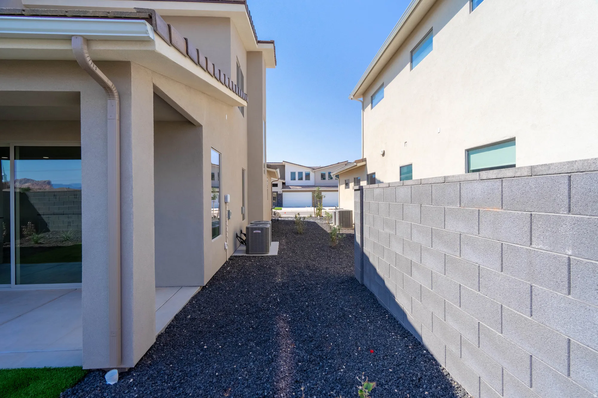 Sliding glass door, stucco exterior, concrete patio, gravel landscaping, block wall perimeter