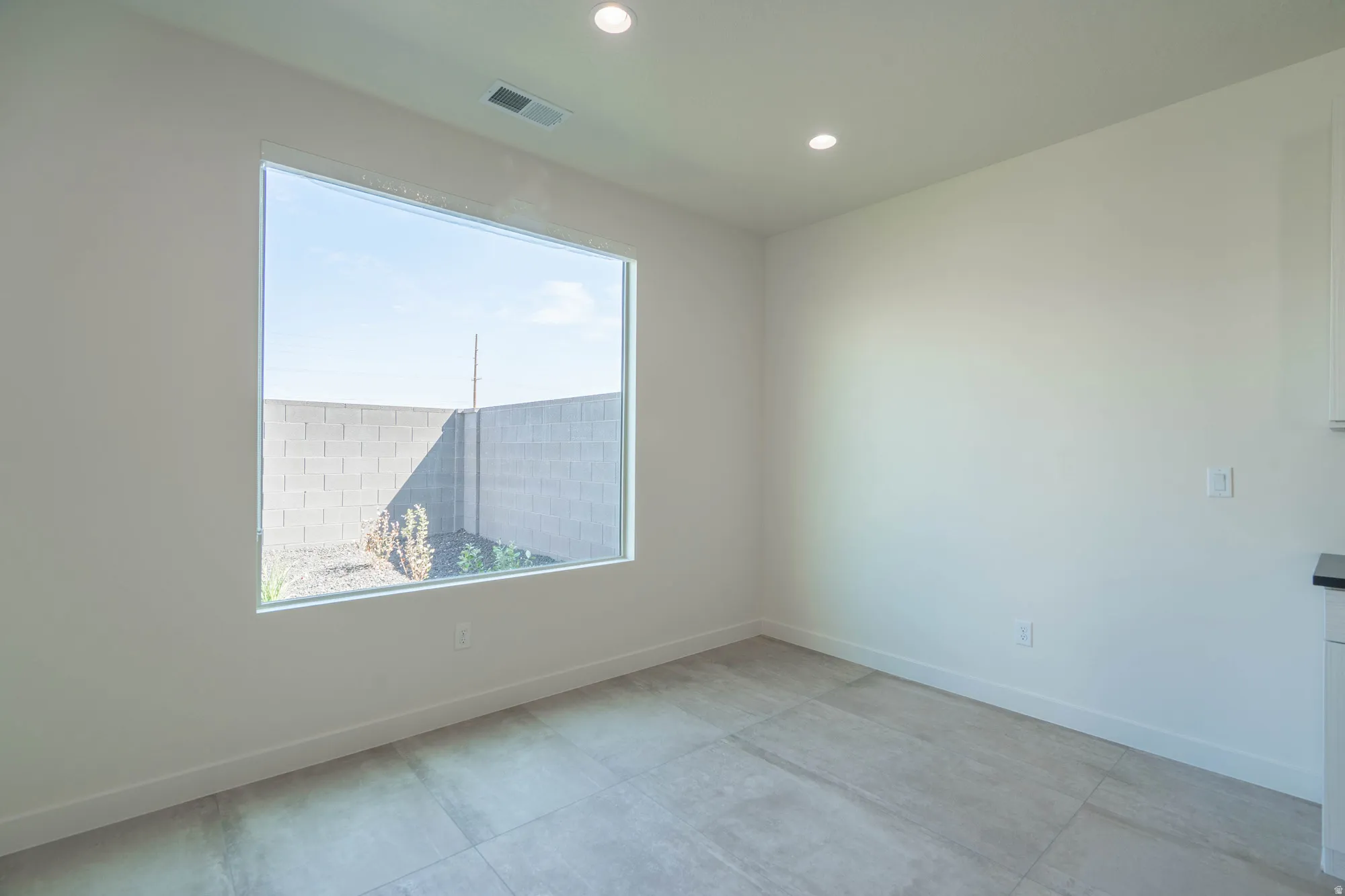 Large picture window, recessed lighting, light-toned walls, tile flooring, and white trim