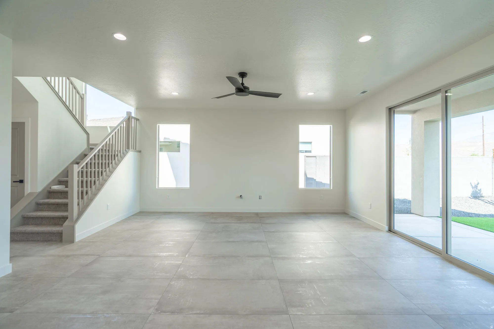 Spacious room featuring large format tile flooring, recessed lighting, a ceiling fan, and sliding glass doors to the exterior