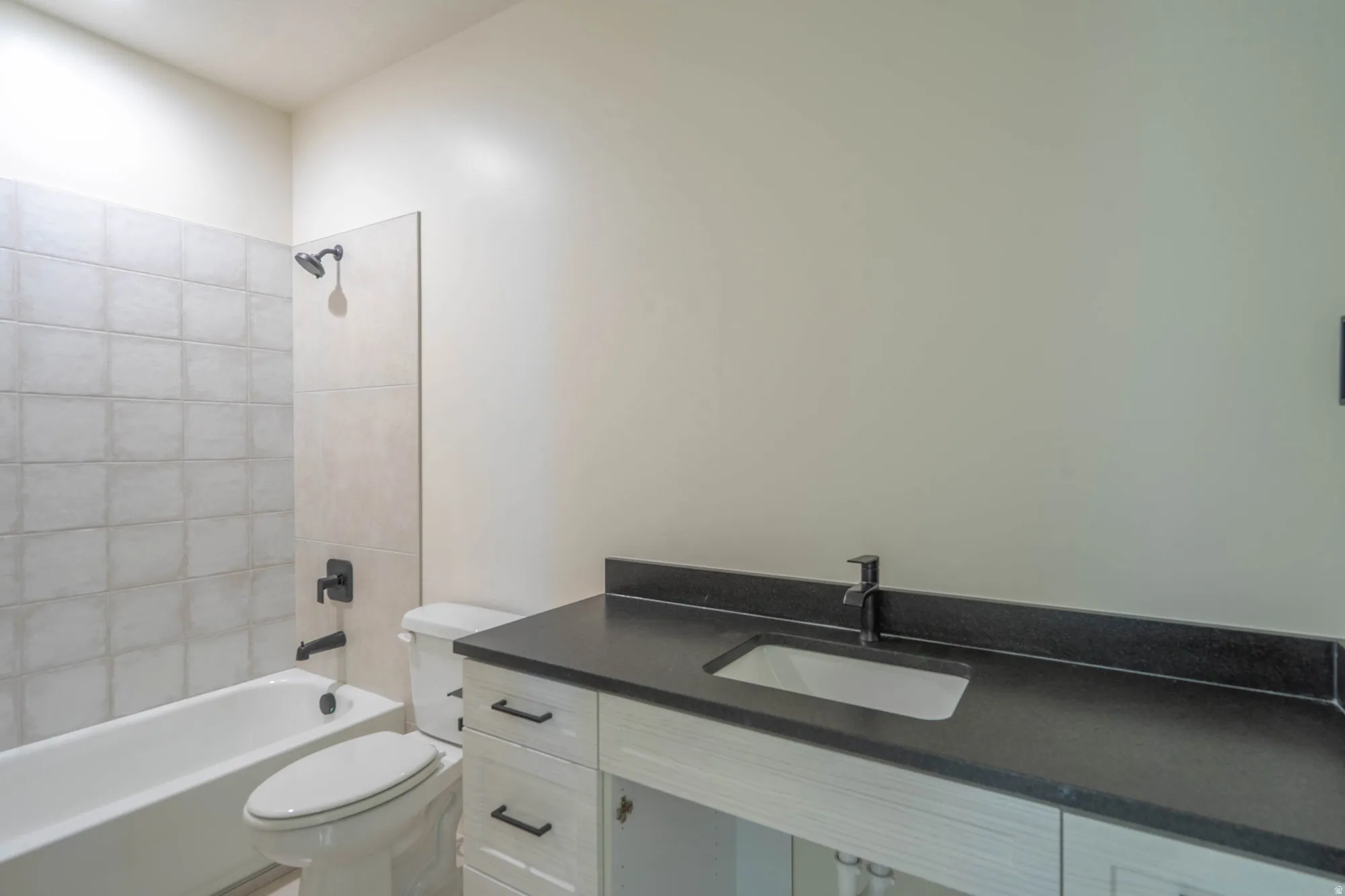 White vanity with black countertop, integrated rectangular sink, and matte black faucet