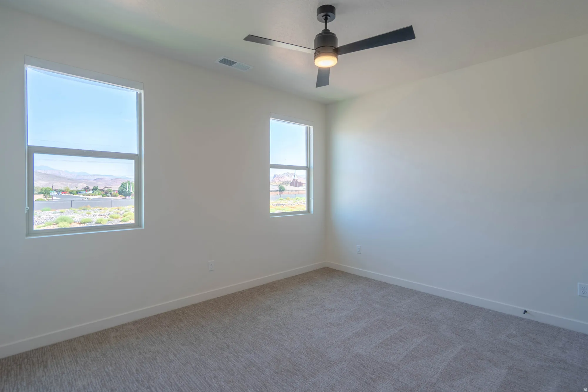 Neutral wall finishes, neutral carpet, ceiling fan, and multiple windows