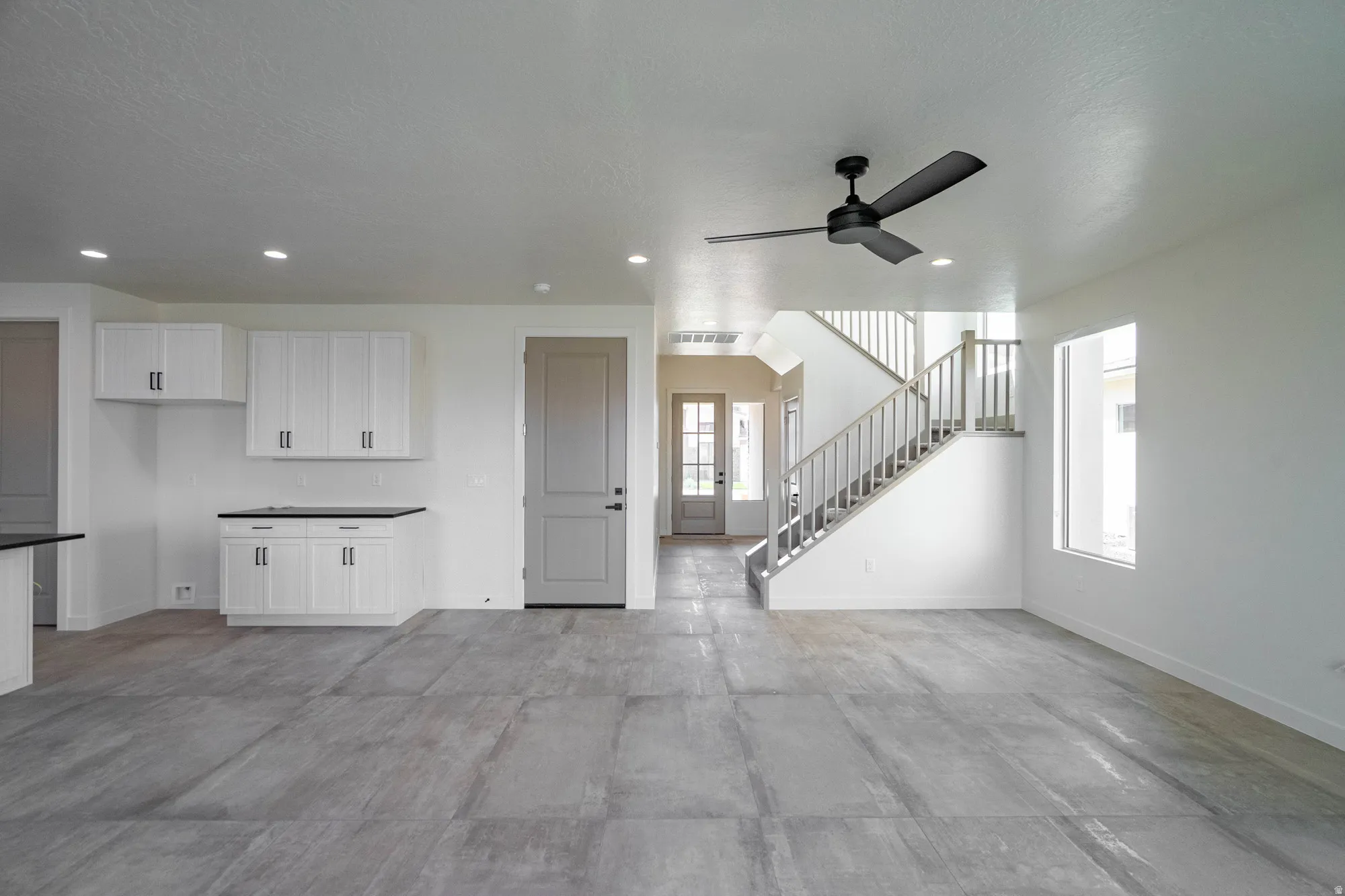 Open-concept living area with large-format tile flooring, recessed lighting, and a contemporary ceiling fan