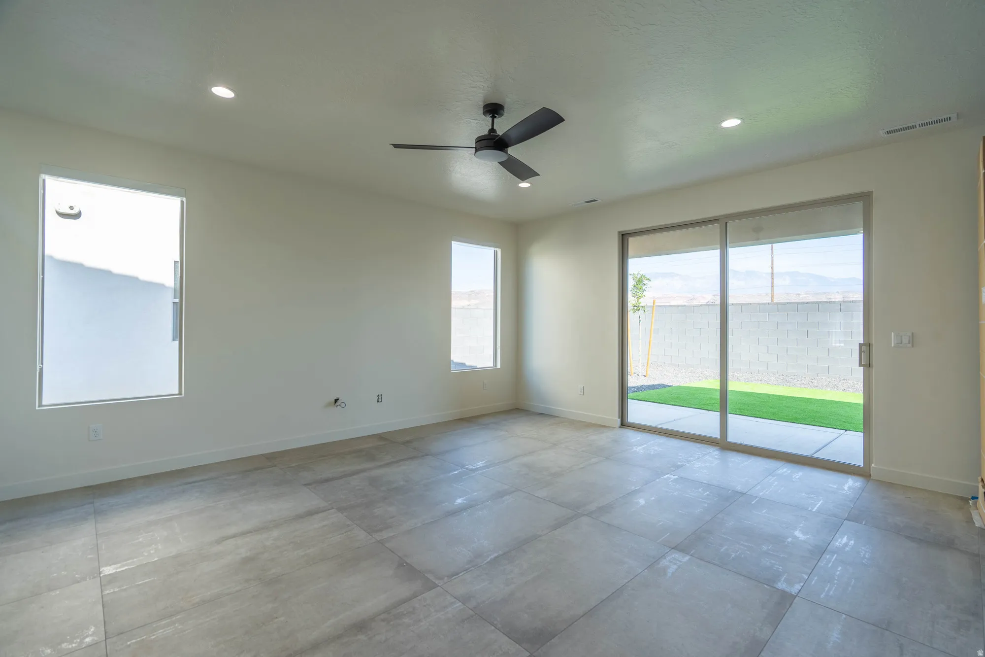 Spacious room featuring large format tile flooring, recessed lighting, and a contemporary ceiling fan