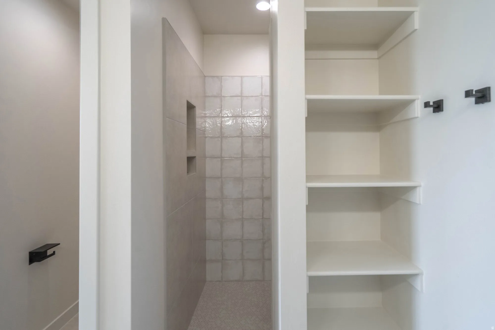 Walk-in shower with tiled walls, integrated niche, and a contrasting tiled floor