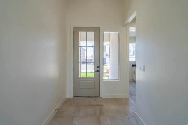Entryway featuring a paneled door with glass inserts, an adjacent vertical window, and tile flooring