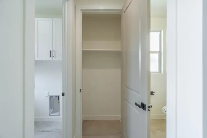 White cabinetry with dark hardware, built-in shelving, and a panel door with dark hardware