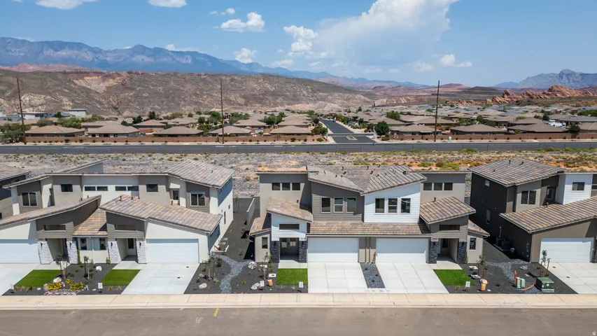 Modern architectural design with multi-level rooflines, integrated two-car garage, stone accents, and low-maintenance landscaping