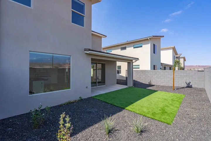 Private backyard featuring a covered patio, artificial turf, and a block wall perimeter