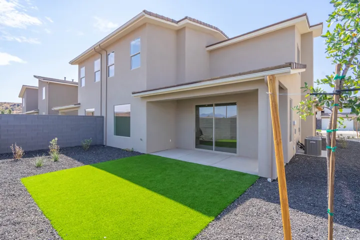 Covered patio with sliding glass doors, artificial turf, and dark gravel landscaping