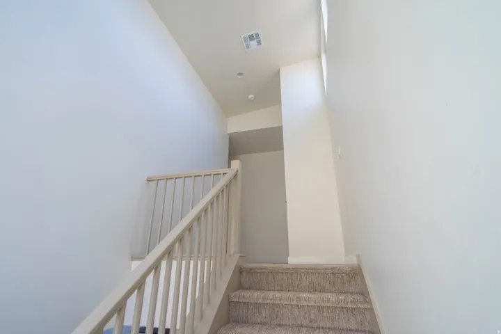 Carpeted staircase with light wood banister and balusters