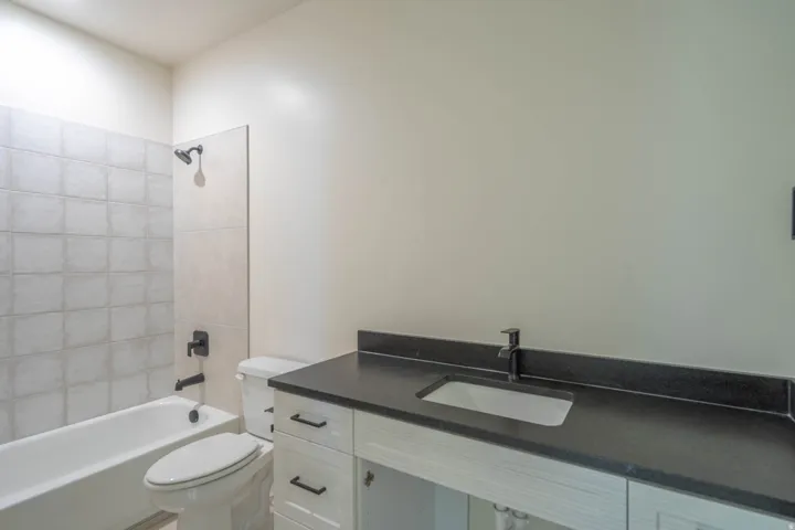 White vanity with black countertop, integrated rectangular sink, and matte black faucet