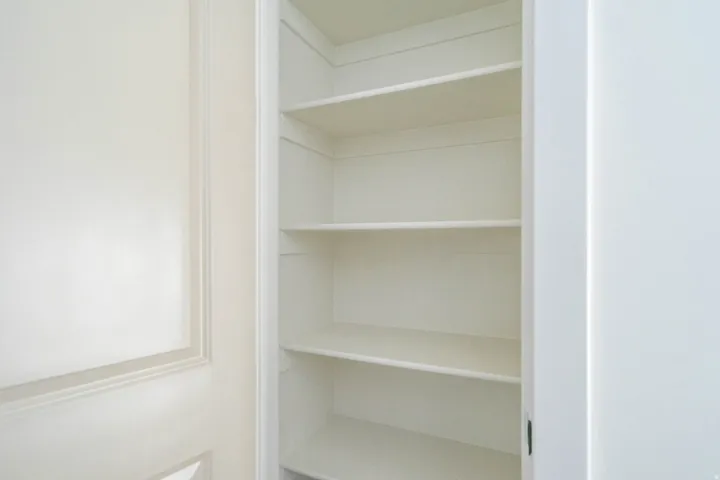 Built-in shelving with multiple levels, white finish, and integrated into a wall recess