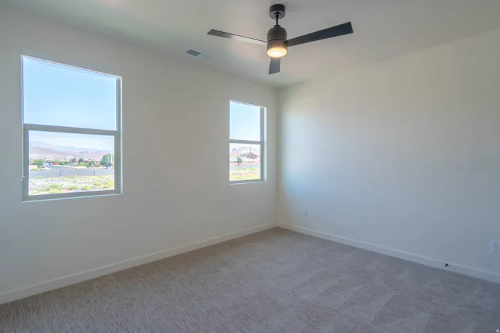 Neutral wall finishes, neutral carpet, ceiling fan, and multiple windows