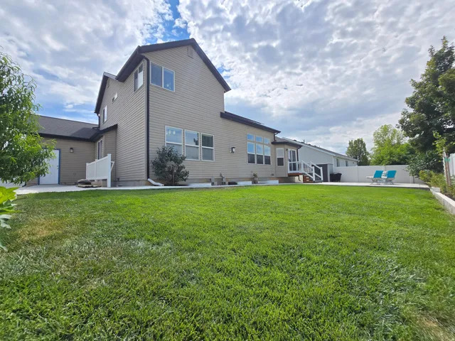 Expansive lawn area with a concrete patio, retaining wall, and mature landscaping
