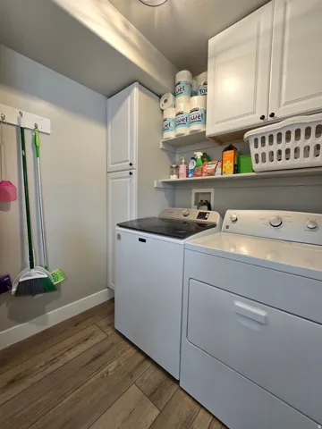 Wood-finish flooring with white baseboards, paired with white wall cabinetry and open shelving