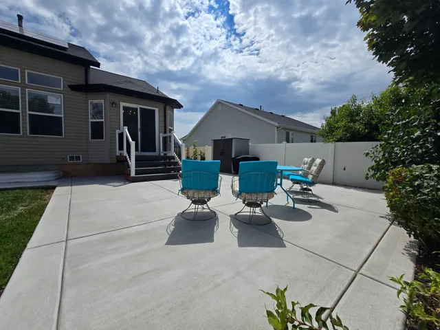 Expansive concrete patio with a white privacy fence and mature perimeter landscaping