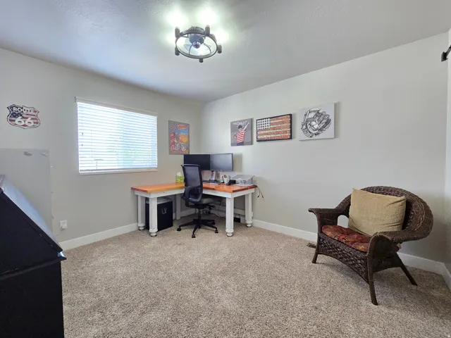 Carpeted room with a ceiling-mounted light fixture, a window with blinds, and light-colored walls