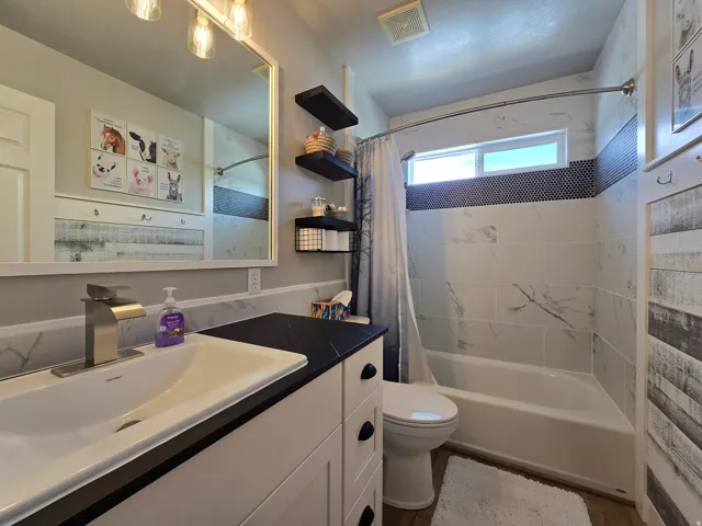 White vanity with black countertop, undermount sink, and brushed nickel faucet
