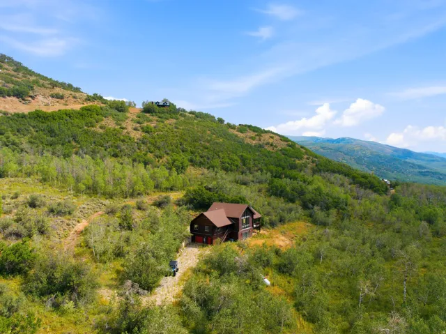 Hillside property with a multi-level structure, a dark-toned exterior, and a reddish-brown roof