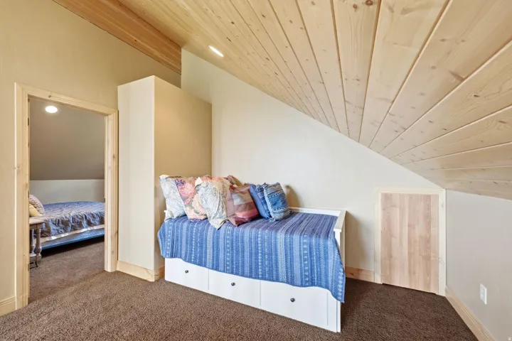 Sloping wood-paneled ceiling, wall-to-wall carpeting, and wood trim details