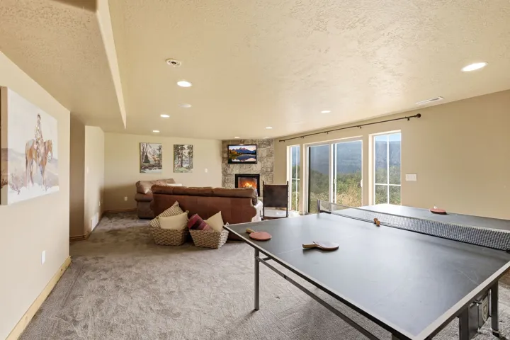 Carpeted living area with recessed lighting, stone-clad fireplace, and sliding glass doors