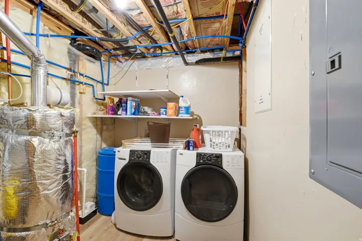Utility area featuring PEX plumbing, exposed wood framing, a water heater, and wall-mounted shelving
