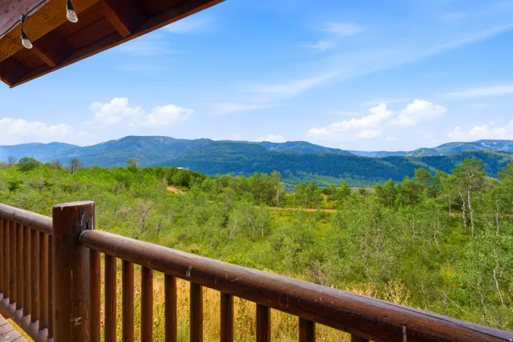 Wood-finish railing with a natural wood-finish post, providing an expansive natural landscape with distant mountains