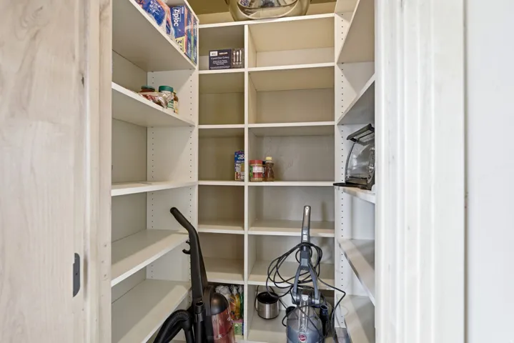 Pantry featuring adjustable shelving, L-shaped configuration, and light-colored finishes