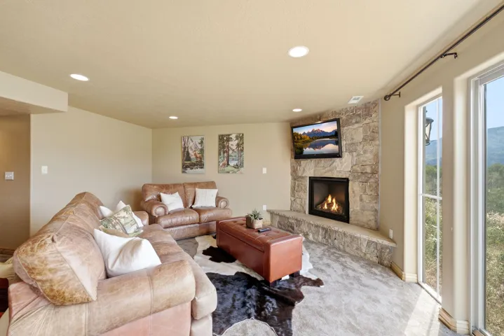 Corner fireplace with stone surround and hearth, recessed lighting, and expansive windows