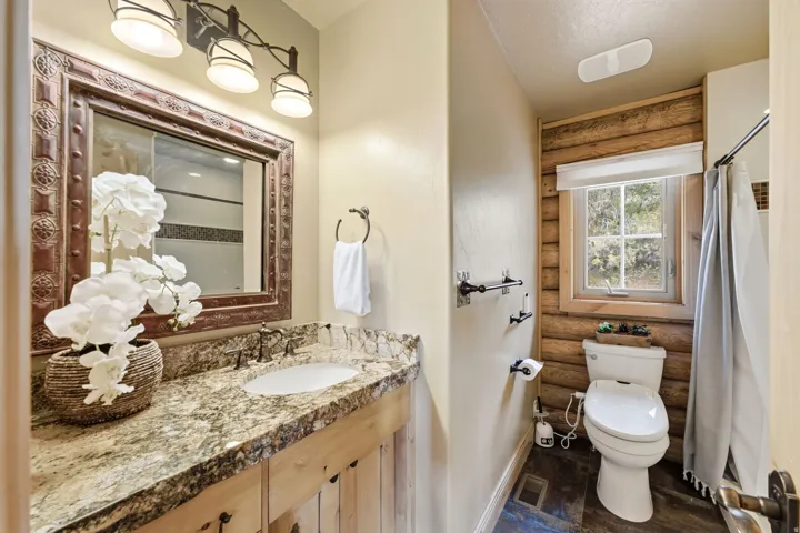 Vanity with granite countertop, integrated sink, and dark bronze hardware
