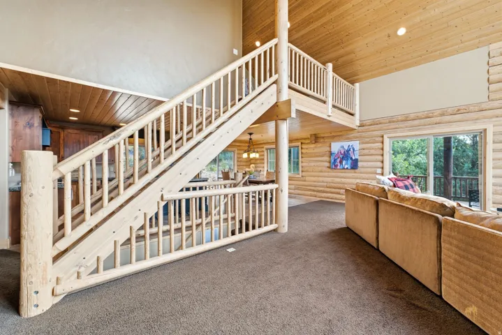 Vaulted wood-paneled ceilings, log-style interior walls, and a wood staircase with natural log railings