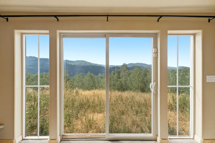 Sliding glass door with an expansive outdoor scenery, flanked by two vertical windows