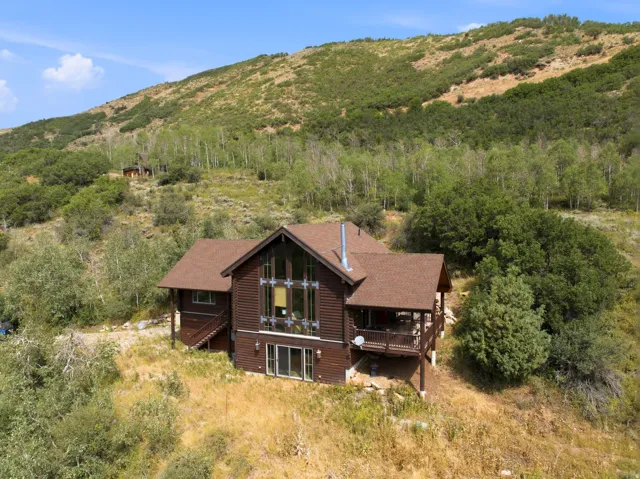 Wood-sided property featuring a multi-story window wall, a covered deck, a lower-level patio door, and a brown shingle roof