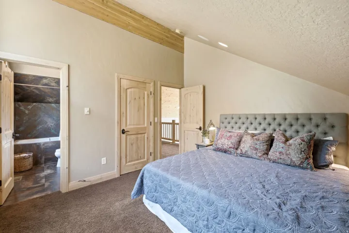 Angled ceiling with wood beam accent, light wood doors, and plush carpet flooring