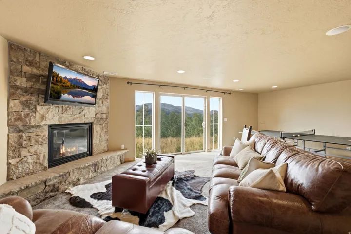 Stone-clad fireplace with mantel, recessed lighting, and glass sliding doors leading to the outdoors