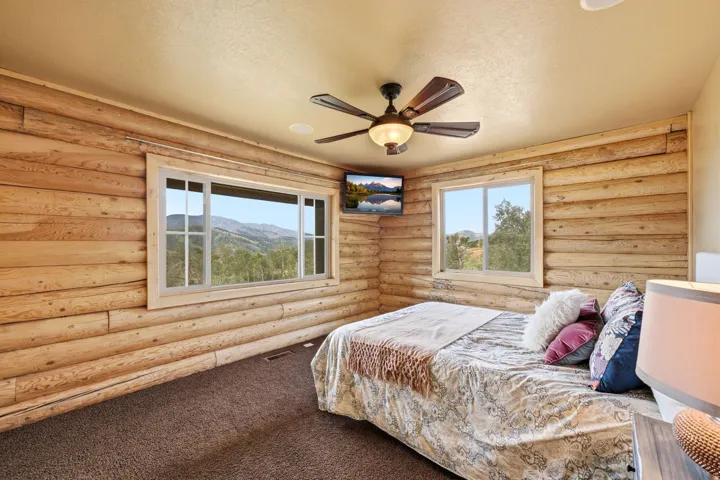 Wood-paneled walls with two large windows, a ceiling fan with integrated lighting, and recessed ceiling lighting
