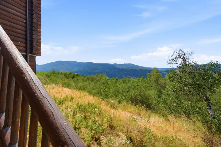 Log-sided exterior with a wooden railing and a mountainous backdrop