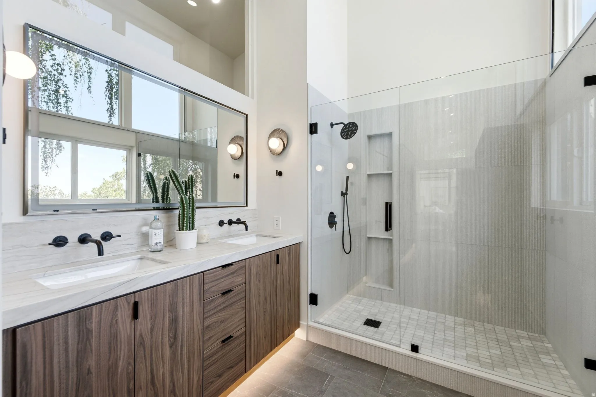Double vanity with integrated sinks, wood-finish cabinetry, and matte black wall-mounted faucets