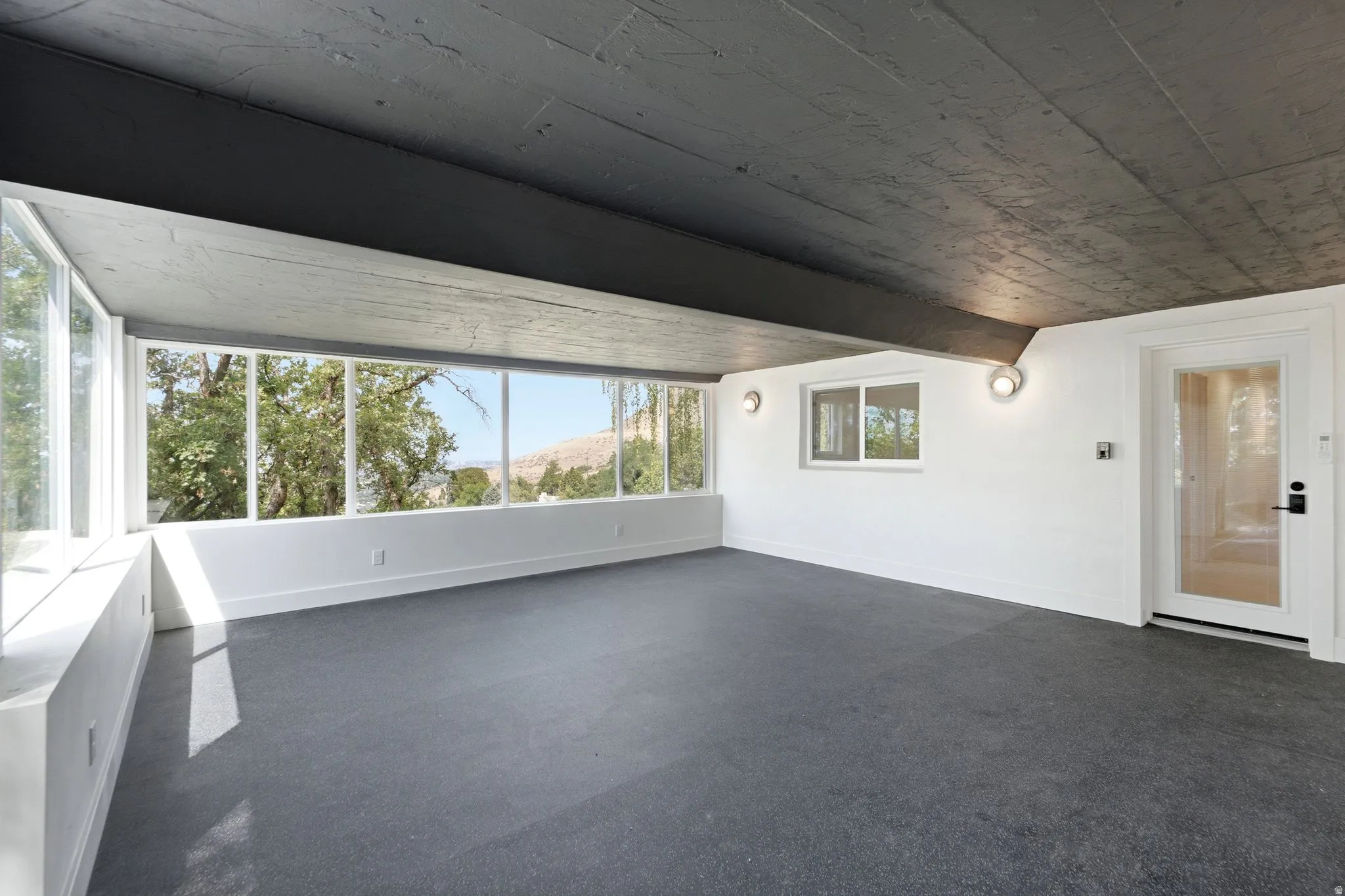 Expansive interior room featuring a wall of windows, a secondary window, and a glass-paneled door