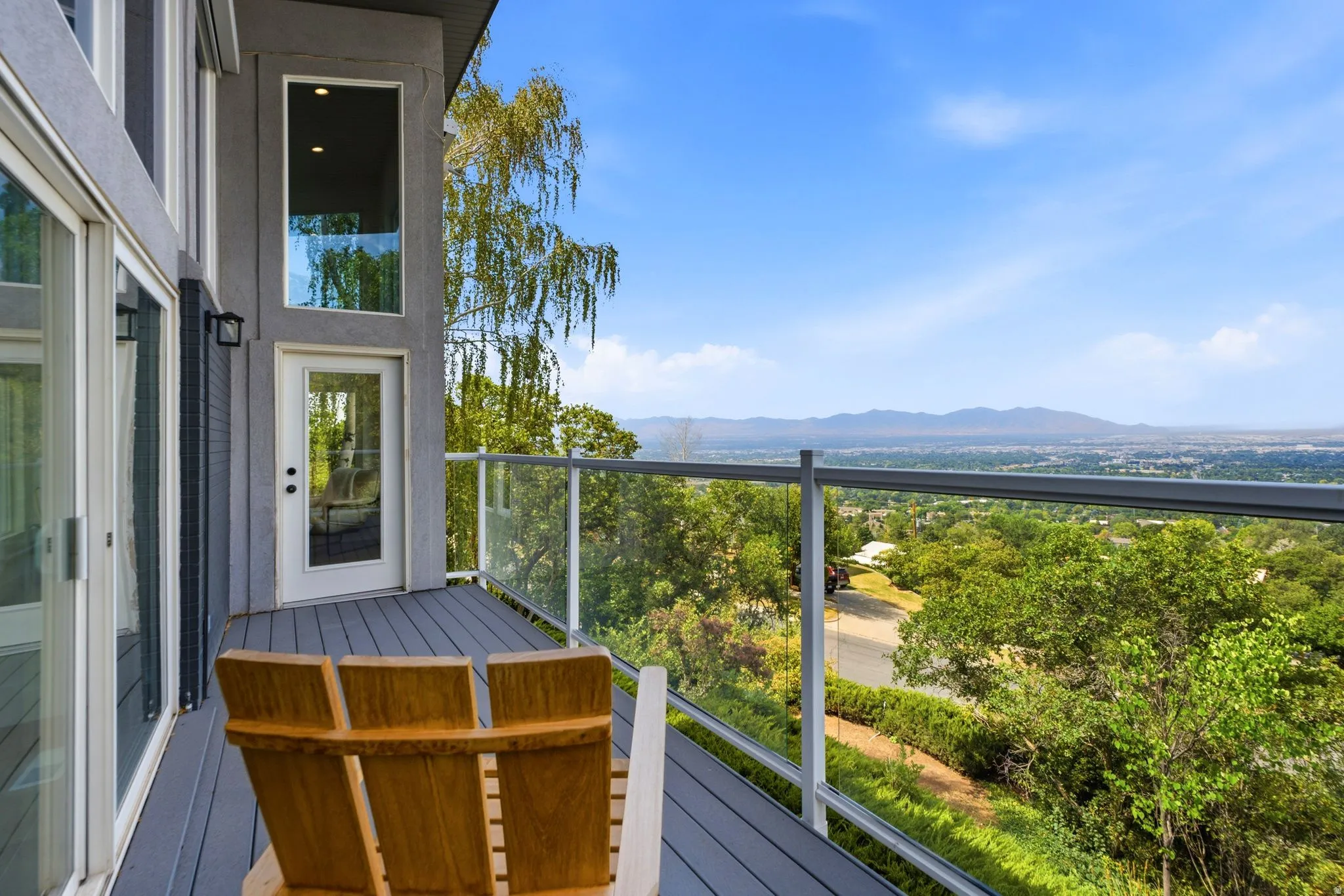 Expansive outdoor deck with composite decking, glass panel railing, and sweeping distant scenery
