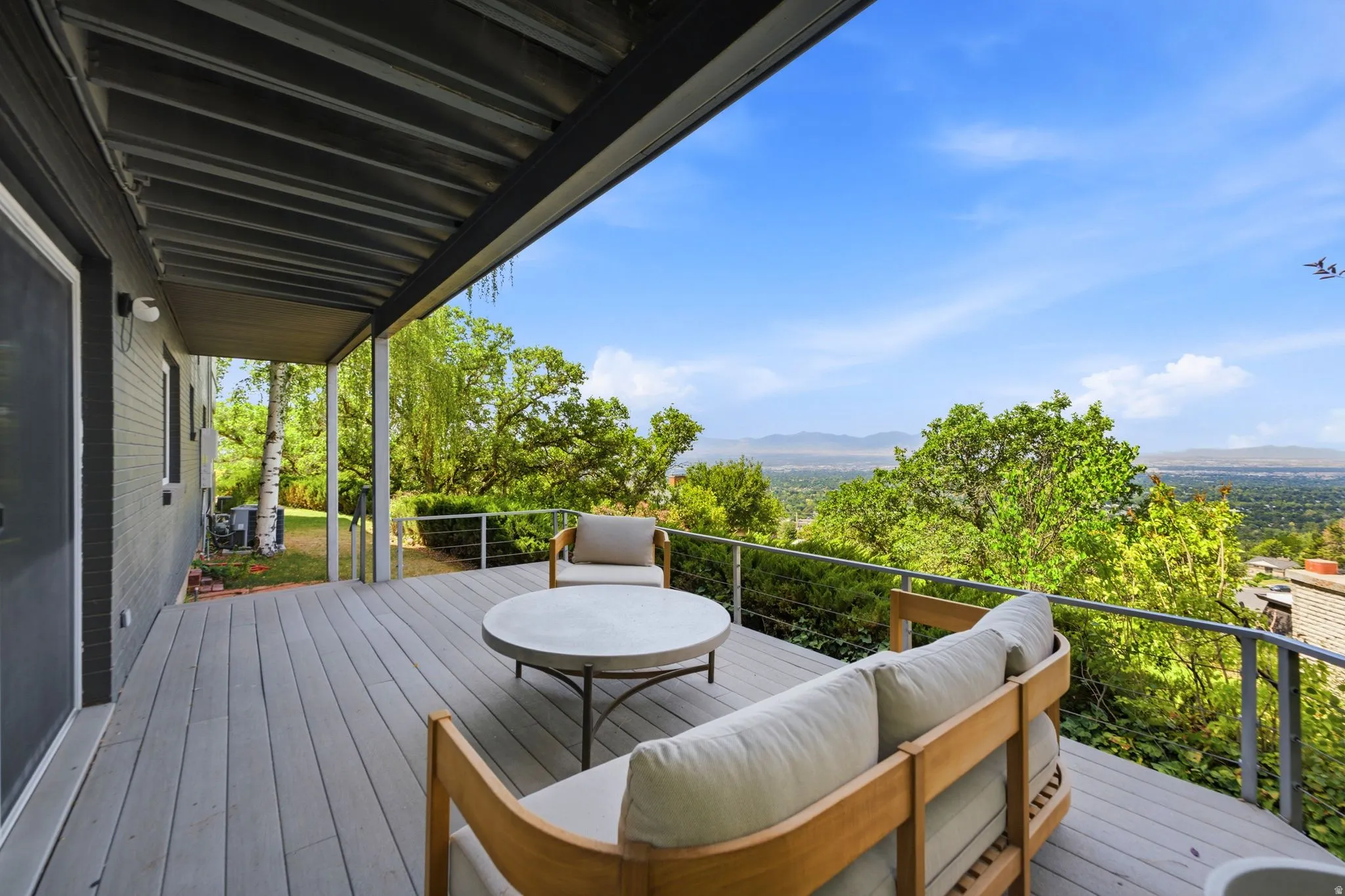 Covered outdoor deck with composite decking, cable railing, and elevated scenery