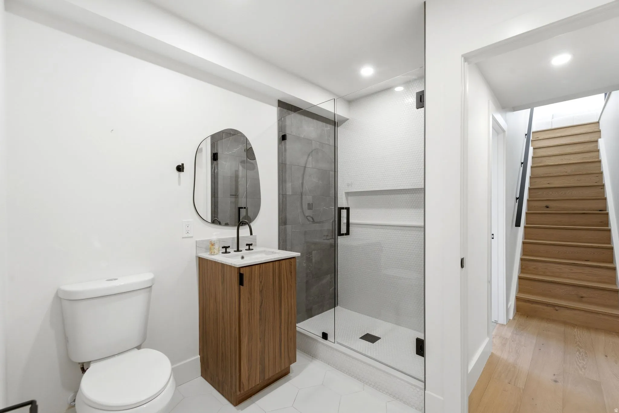 Bathroom featuring a glass-enclosed shower, wood-finish vanity with countertop, and modern black fixtures