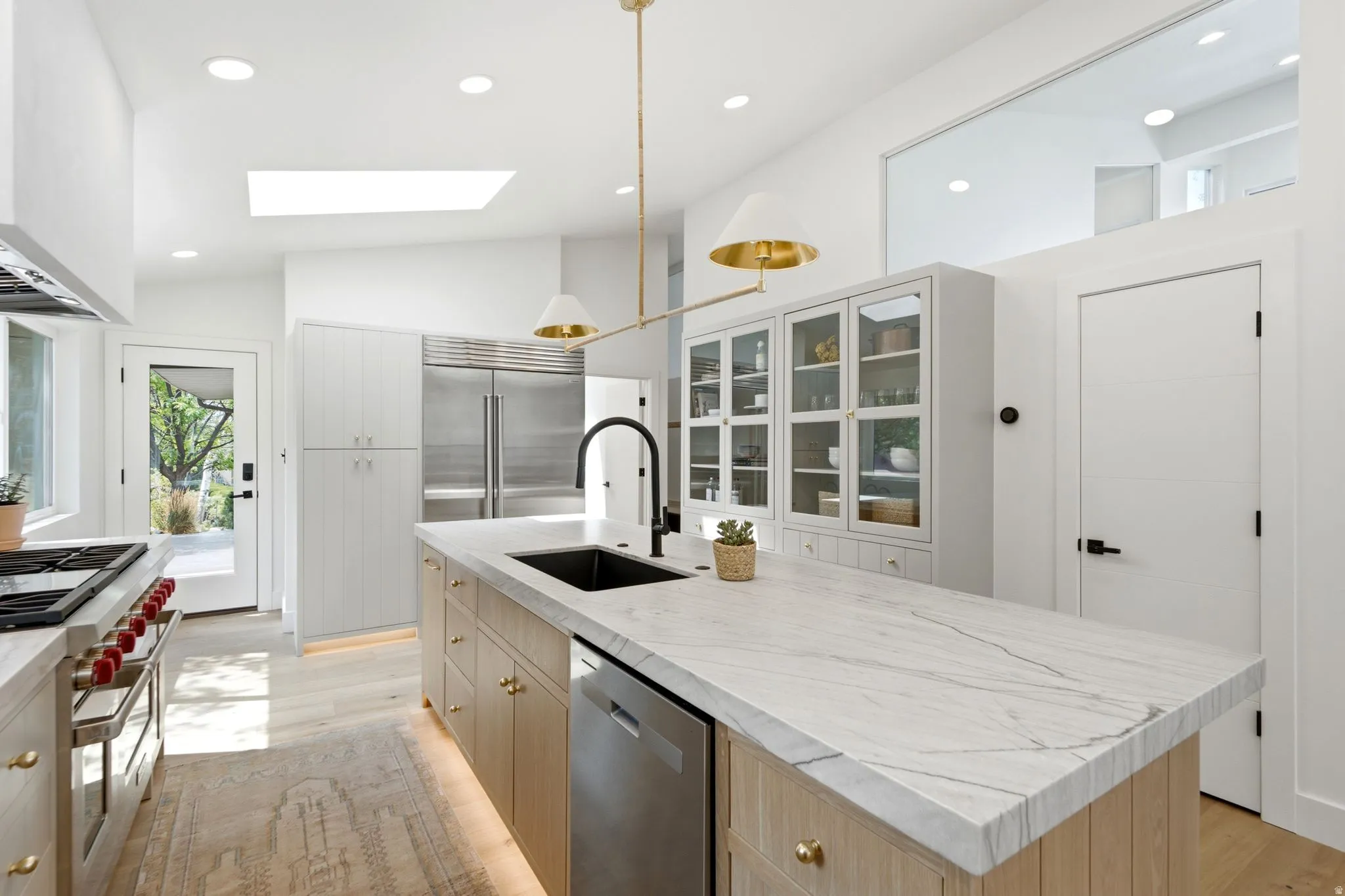 Kitchen featuring a substantial island with stone countertop, stainless steel appliances, recessed lighting, and a skylight