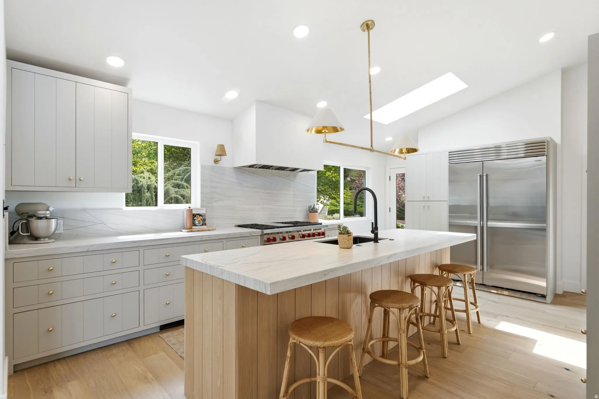 Gourmet kitchen featuring a large island, stainless steel appliances, light wood-finish flooring, and a skylight