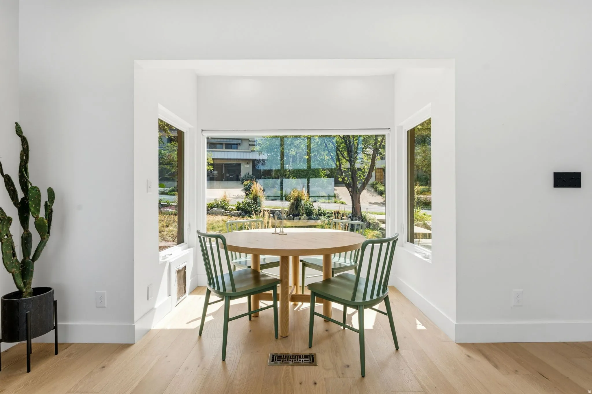 Recessed alcove with expansive windows, light wood-finish flooring, and white painted walls