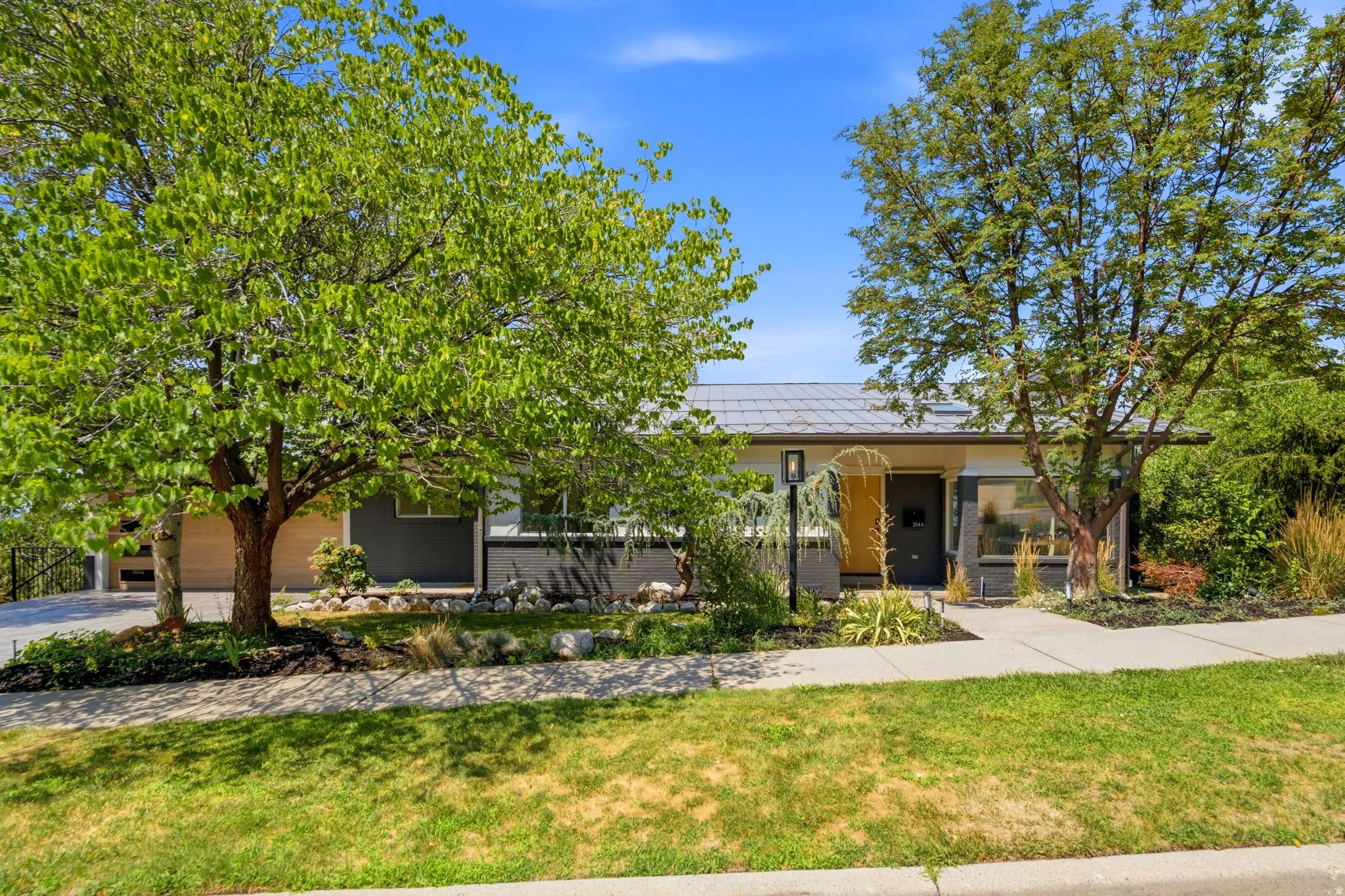Mid-century modern exterior with a grey tile roof, contemporary light fixture, and a vibrant yellow entry door