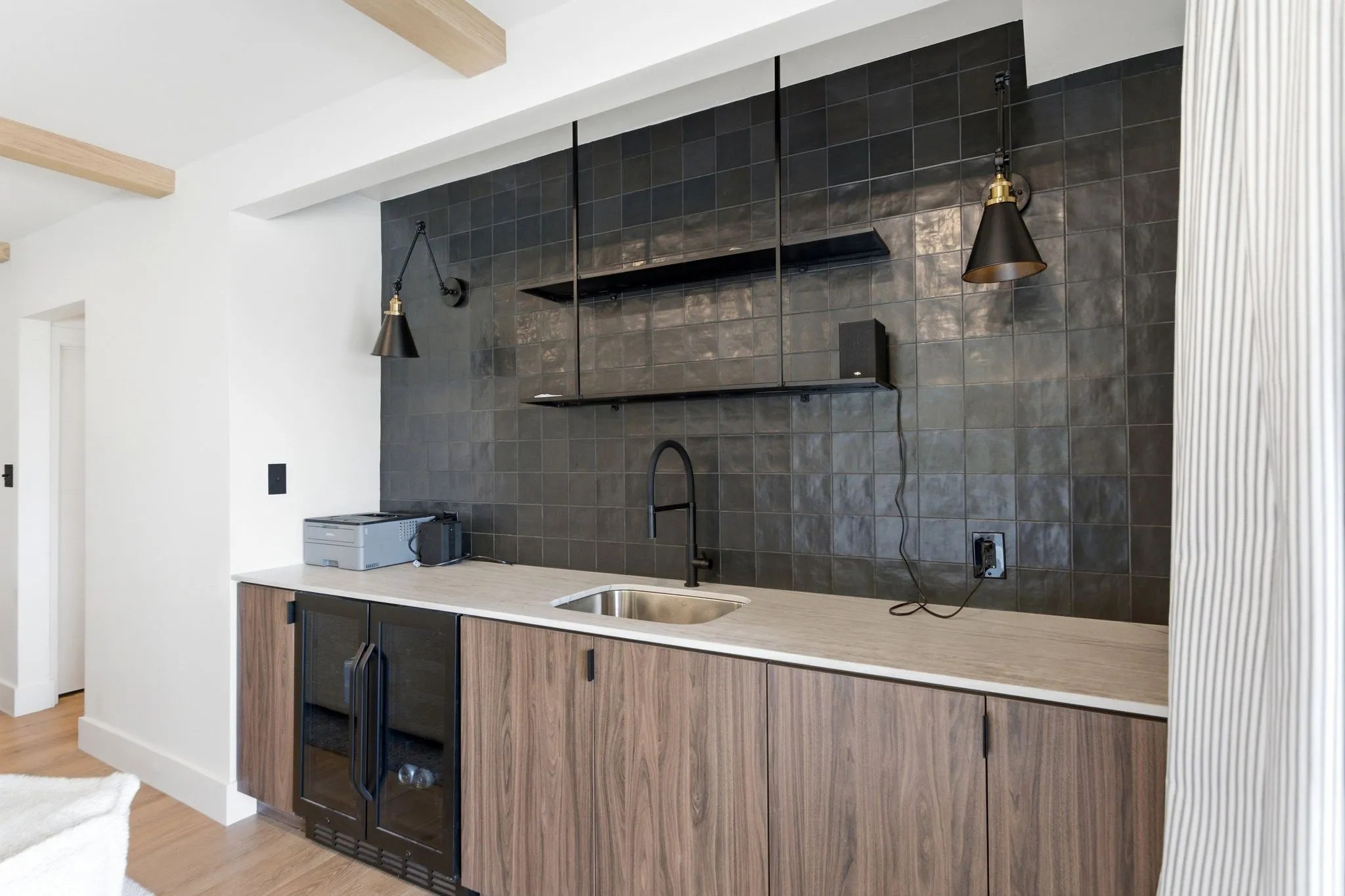 Built-in bar with wood-finish cabinetry, integrated beverage cooler, undermount sink, and dark tile backsplash